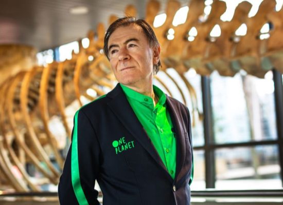 Bedrijfskleding One Planet Jas/vest en blouse Medewerker staat voor een skelet van een dinosaurus