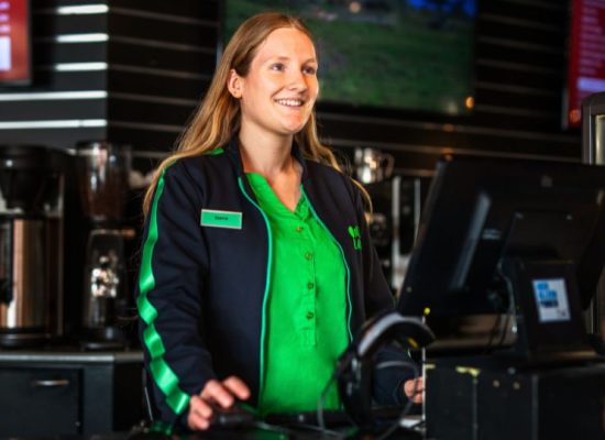 Bedrijfskleding One Planet Vest en blouse Medewerker staat achter de kassa van een restaurant