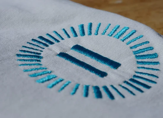 Geborduurd Landal-logo op een wit kledingstuk.