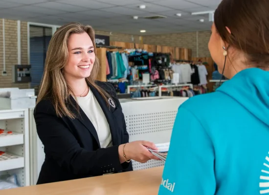 Medewerker van Landal helpt een gast bij de receptie van een vakantiepark.