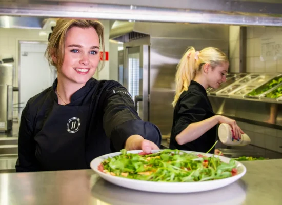 Twee medewerkers van Landal bereiden verse gerechten in een professionele keuken.