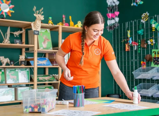 Landal medewerker bereidt een creatieve kinderactiviteit voor aan een knutseltafel.