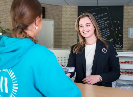 Medewerker van Landal helpt een gast aan de receptiebalie van een vakantiepark.